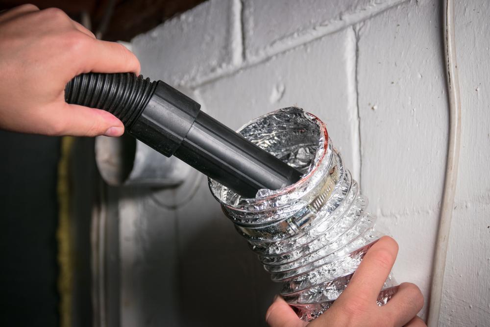Duct cleaning concept Hand holding an air duct and using a vacuum to suck out dust