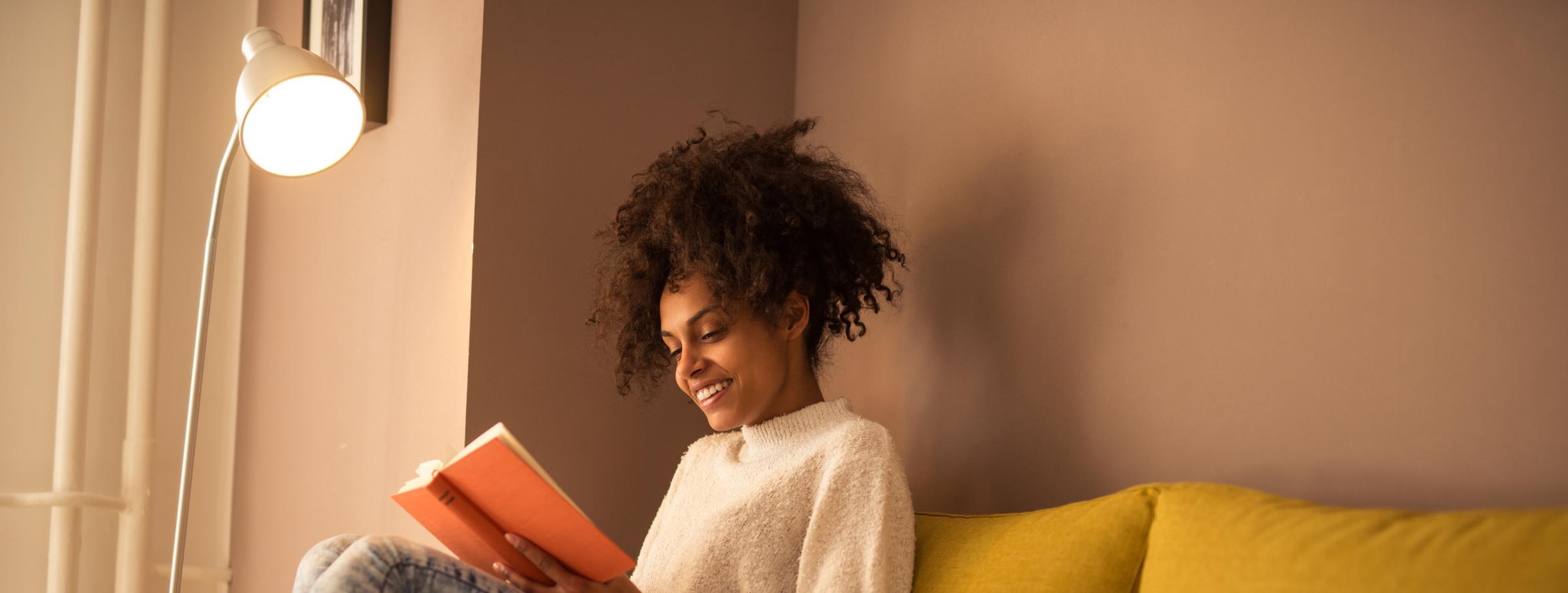 Woman reading a book under a lamp